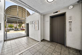 A hallway with a brown elevator and a white wall.